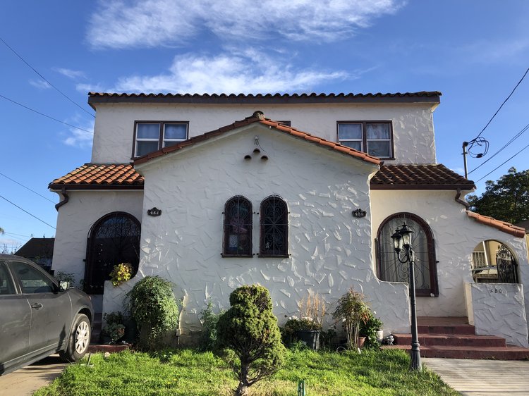 A white adobe duplex with a green front lawn.